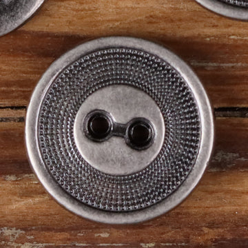Close-up of a 2-hole metal button with concentric circle edge texture, silver finish
