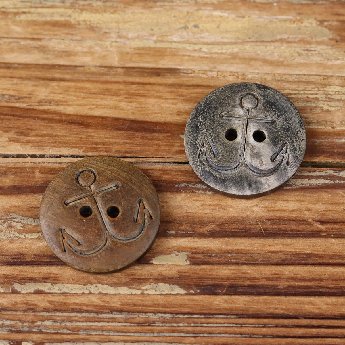 Two anchor buffalo horn buttons, dark gray and brown, each with four holes
