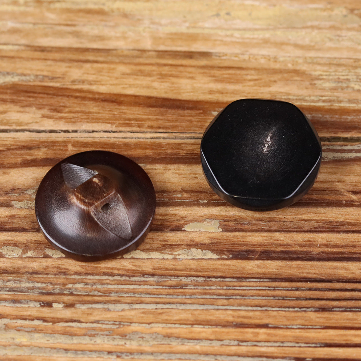 Two buffalo horn buttons with recessed eye detail and irregular front edges