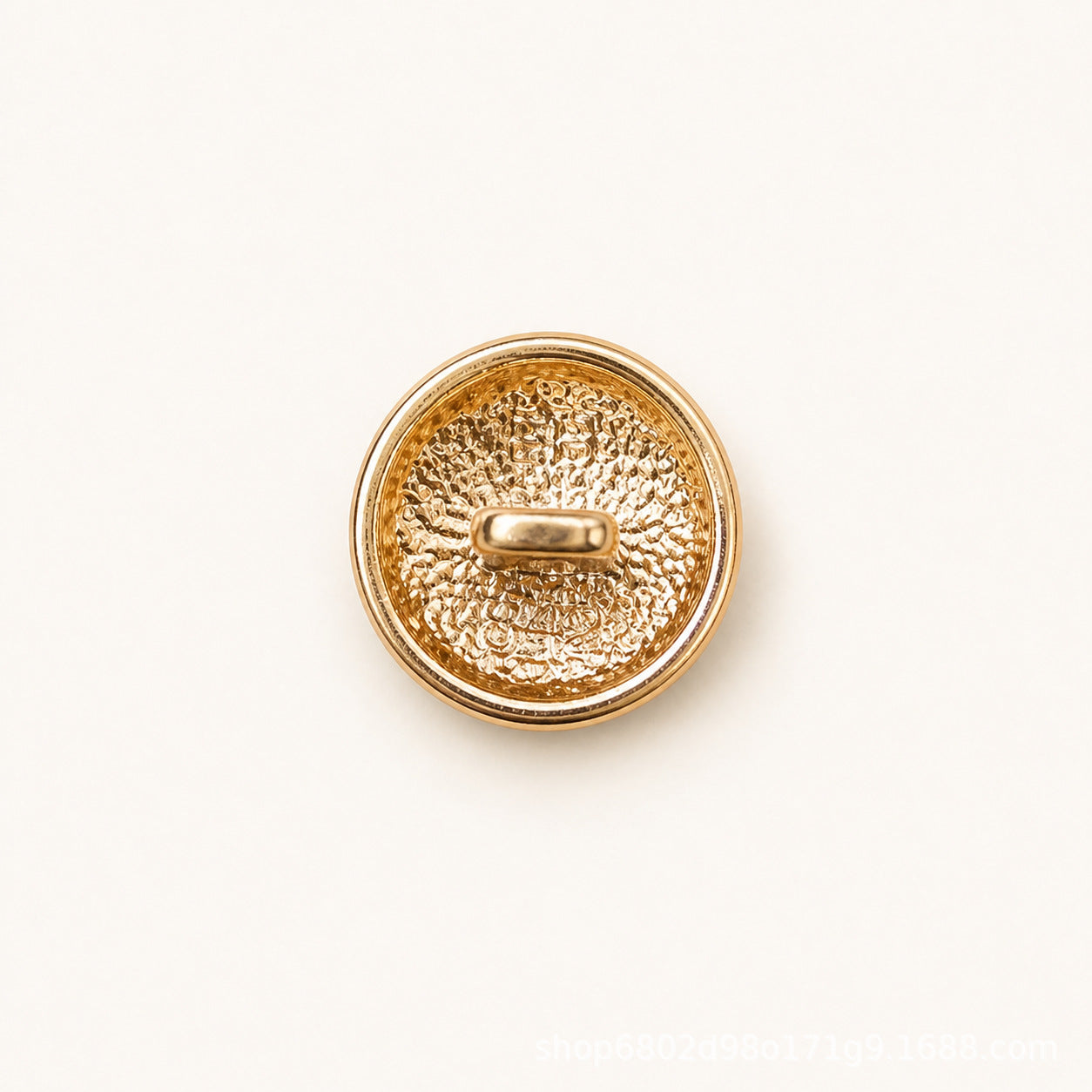 Round metal shank button, textured gold back with oval shank and gold rim