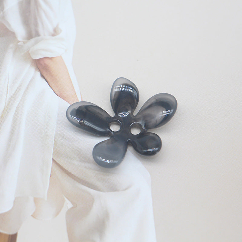 Black-grey ombré 5-petal resin flower sewing button with two holes.