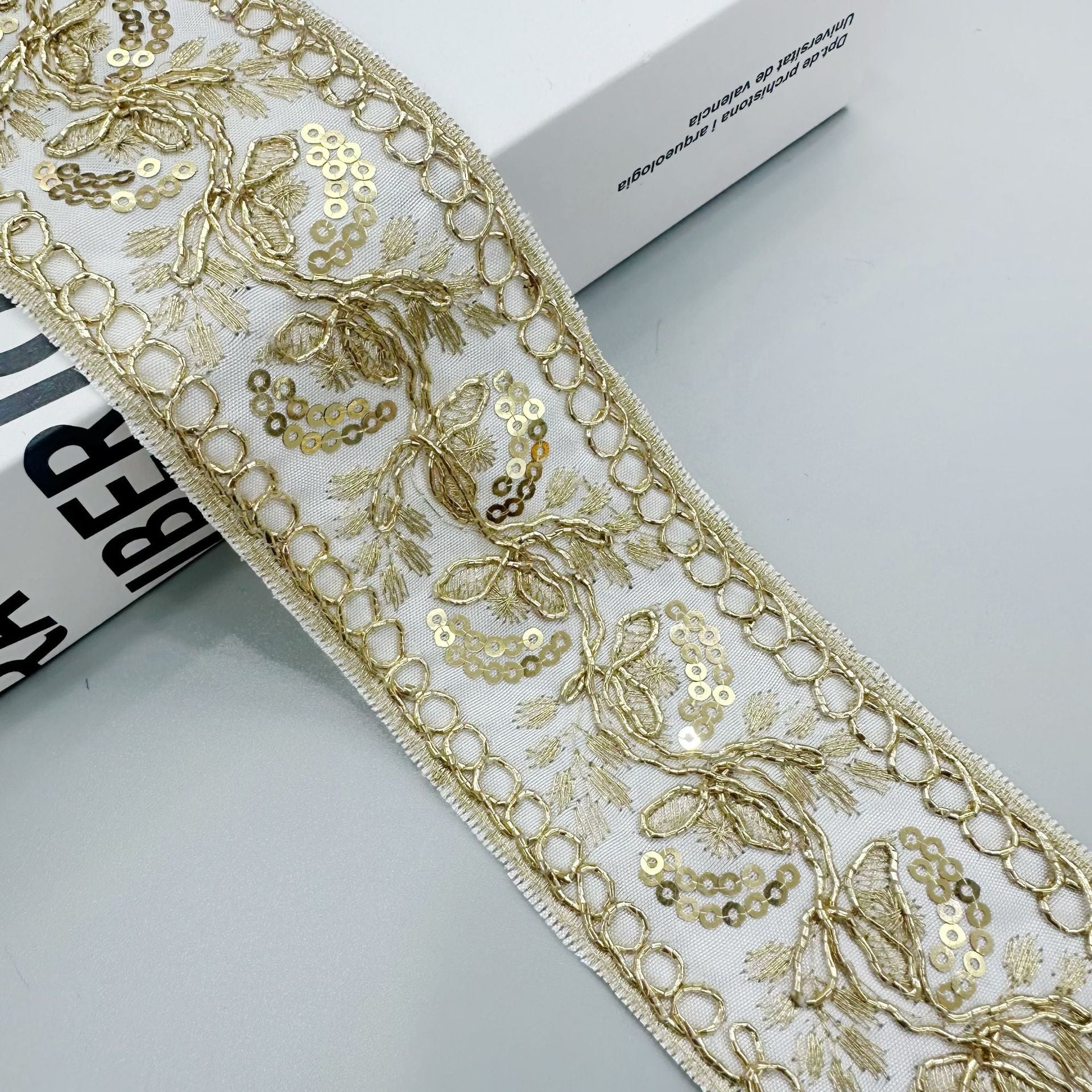 Gold sequin embroidered lace trim ribbon in ivory/white with ornate floral motifs