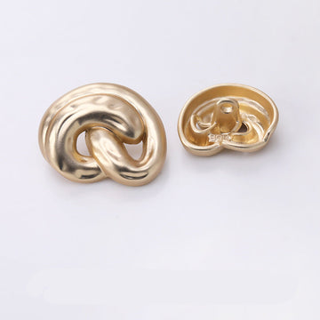 Gold ear-shaped metal shank button, swirl cutout front