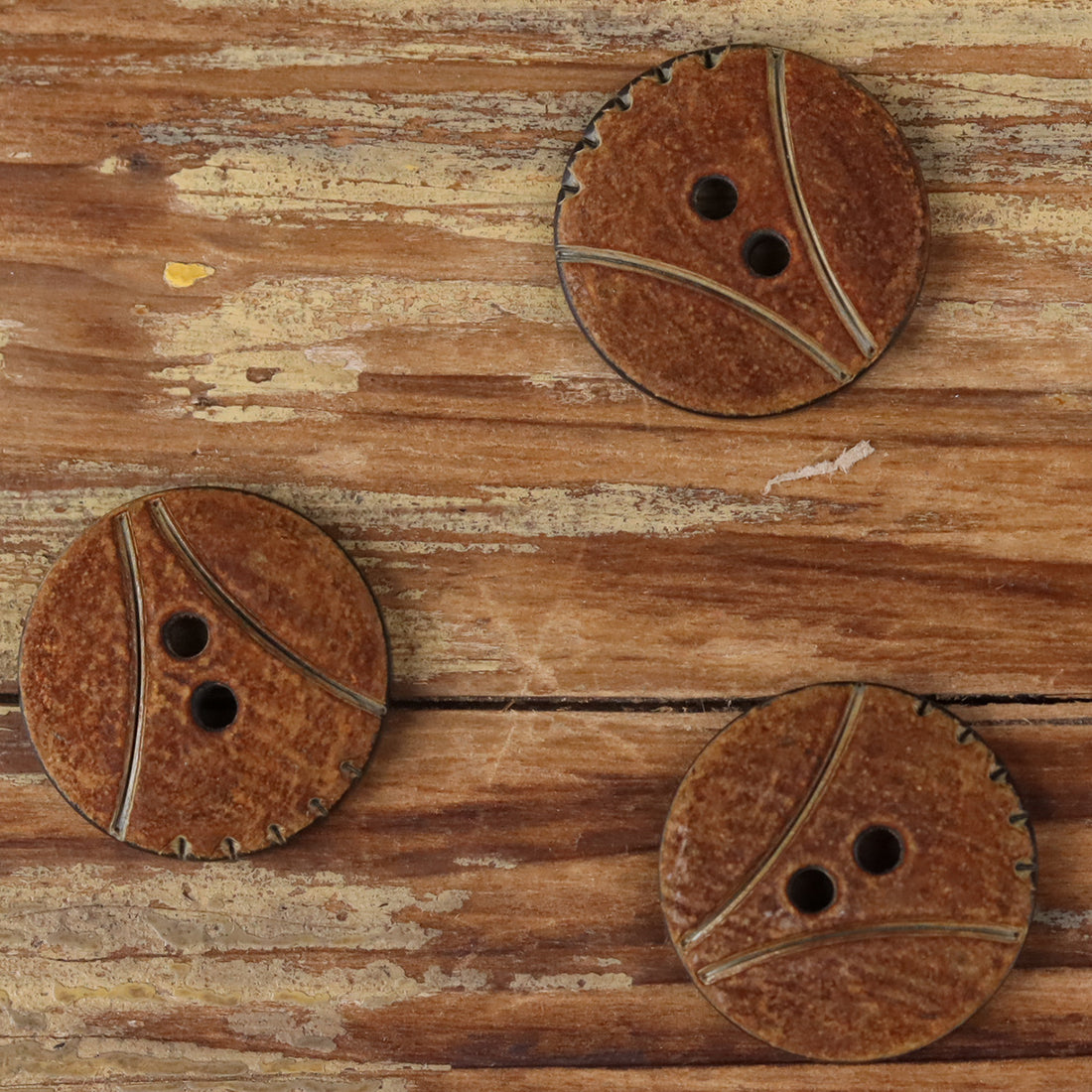 Round 2-hole horn button with scorched finish, two holes and dark curved grooves