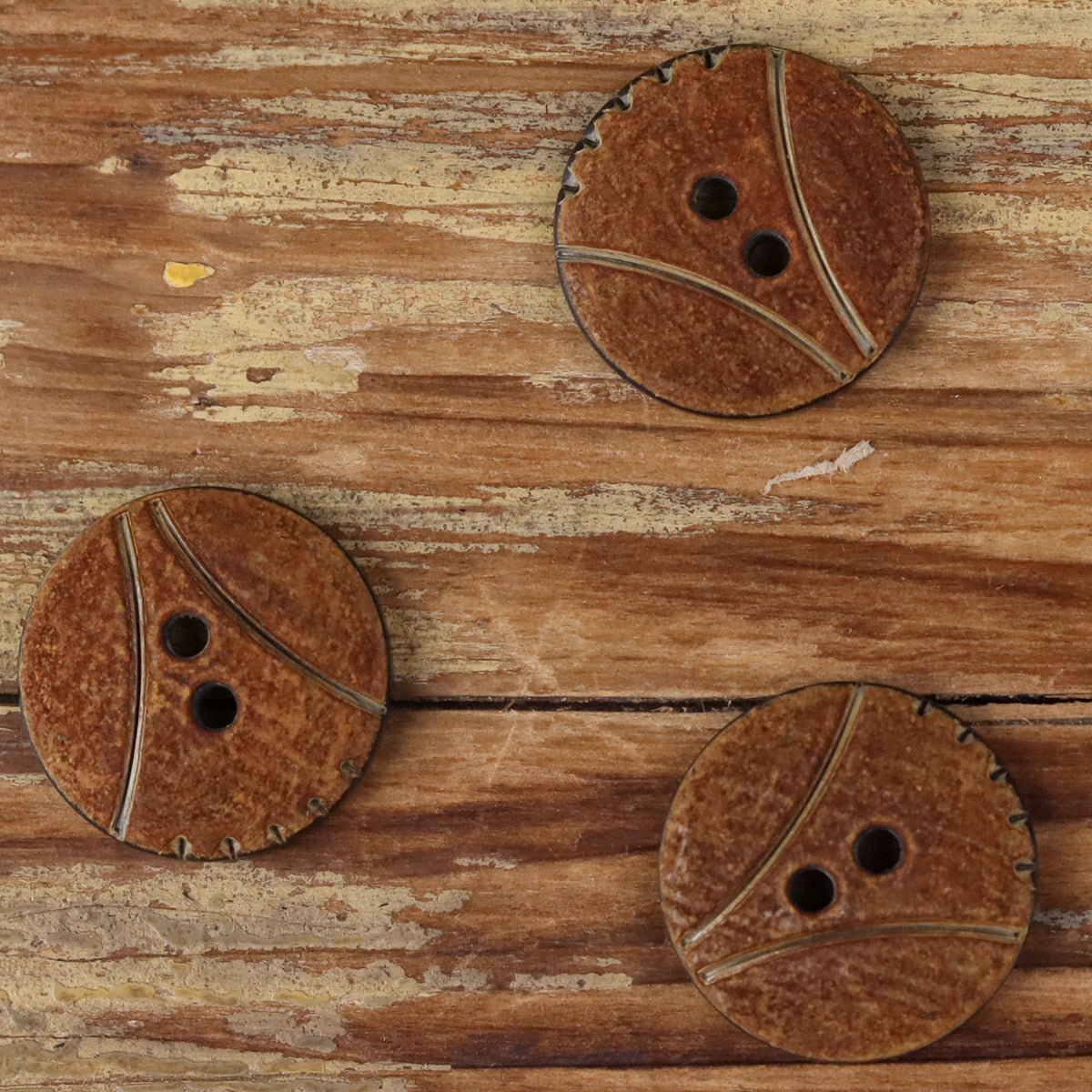Round 2-hole horn buttons with scorched finish, three buttons shown on wood