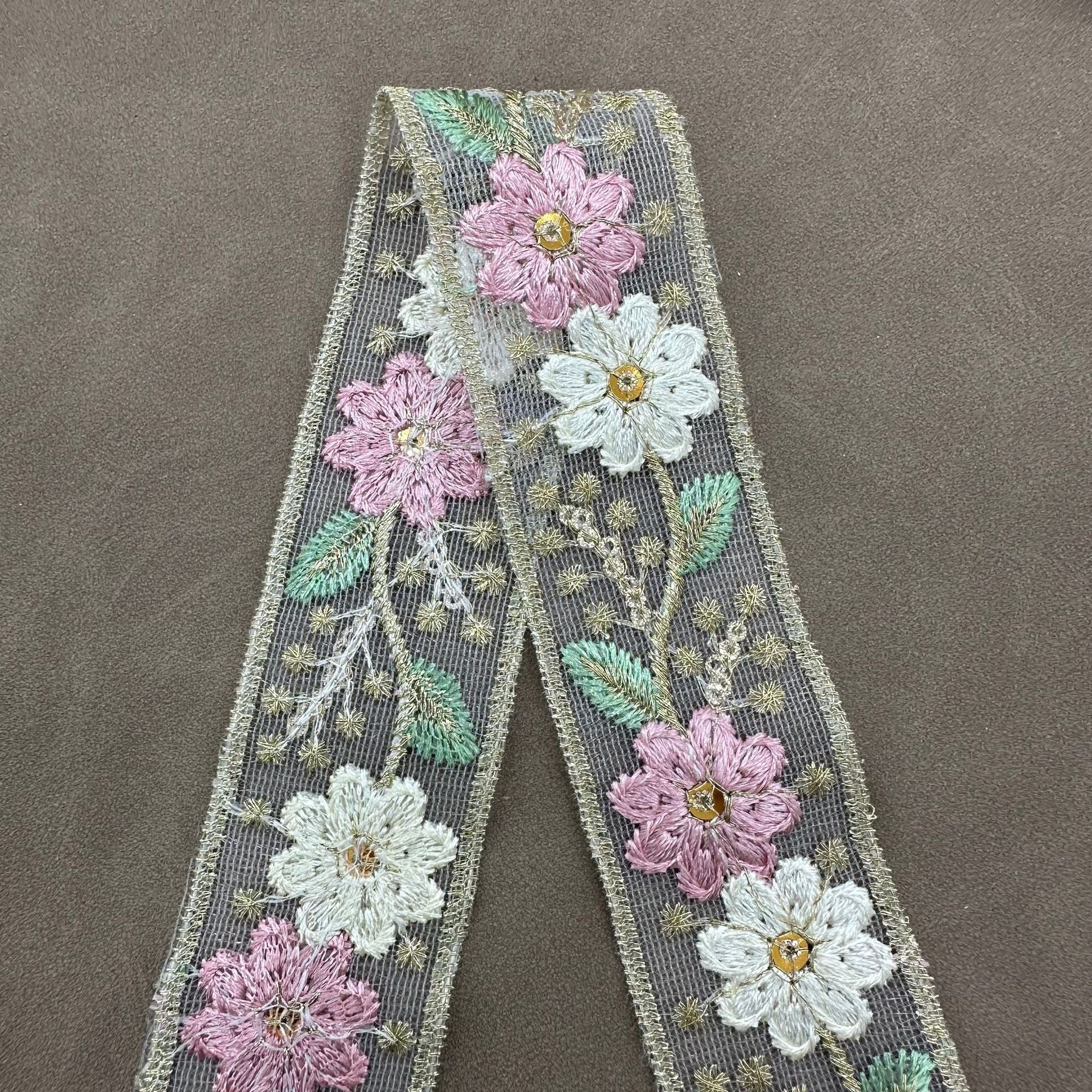 Pink mesh lace trim with embroidered flowers and green leaves, framed by gold trim border