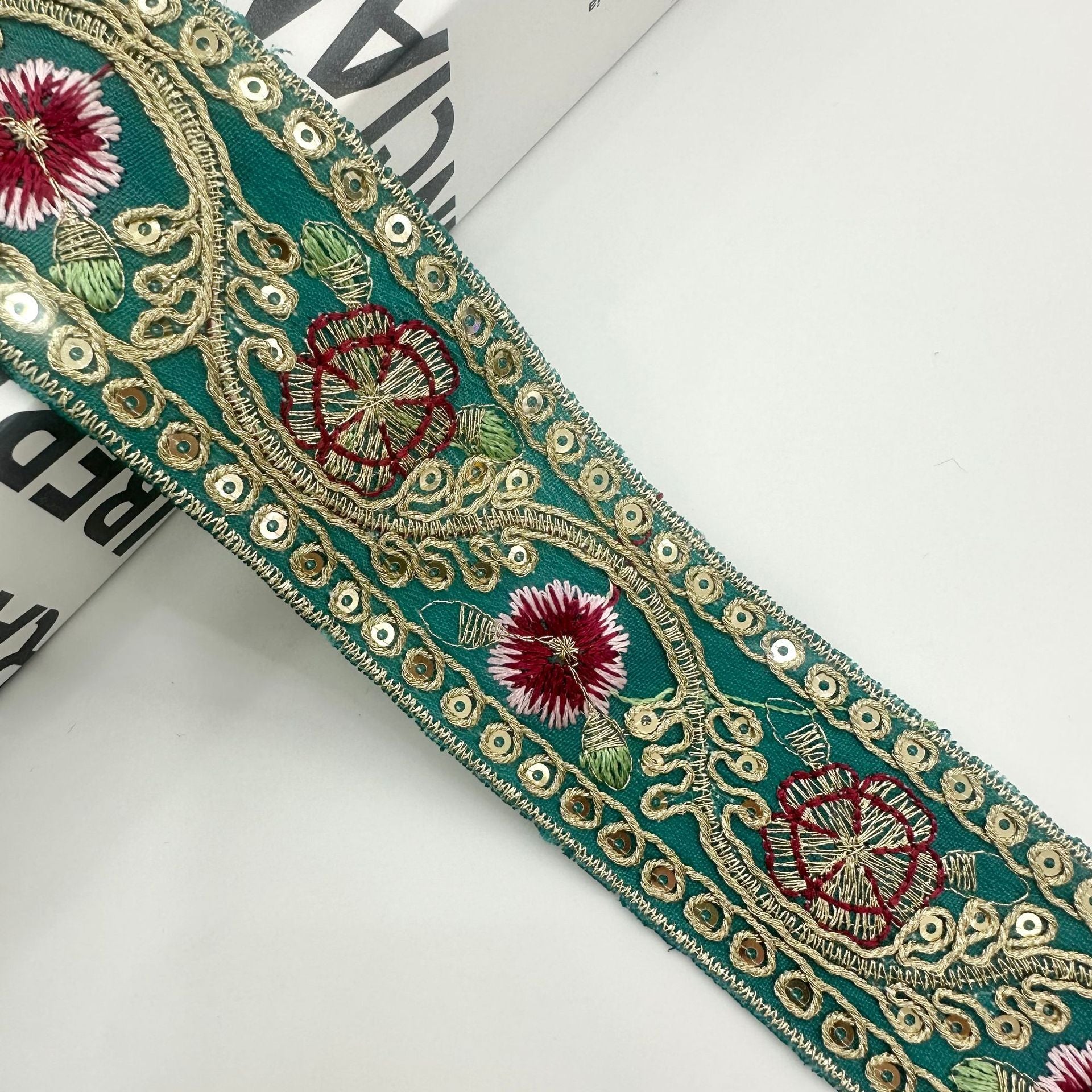 Türkisgrüner bestickter Besatz mit roten Blüten, rotem Blumenmuster und goldenen Zierösen
