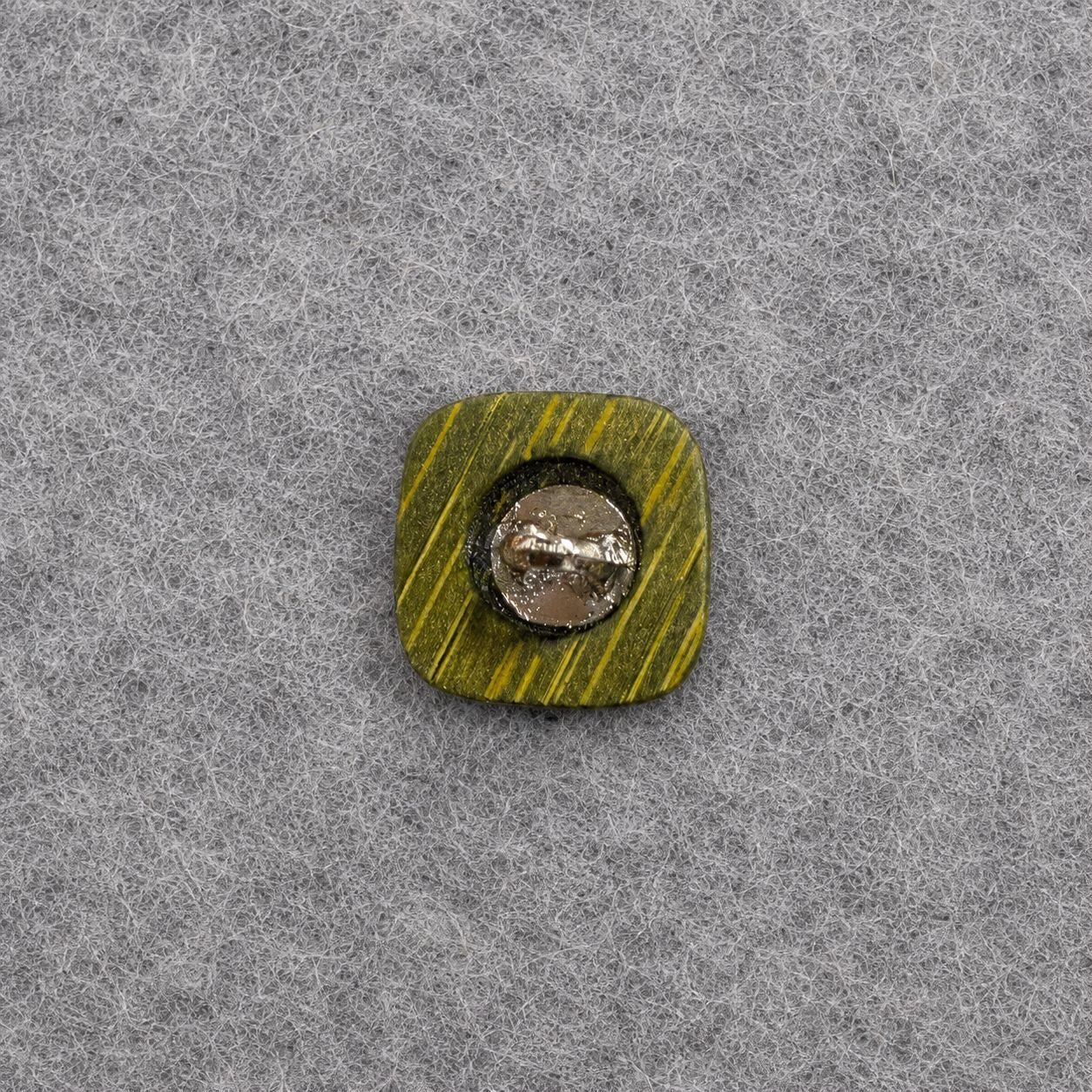 Green square shank button with visible metal shank plate and cross grooves