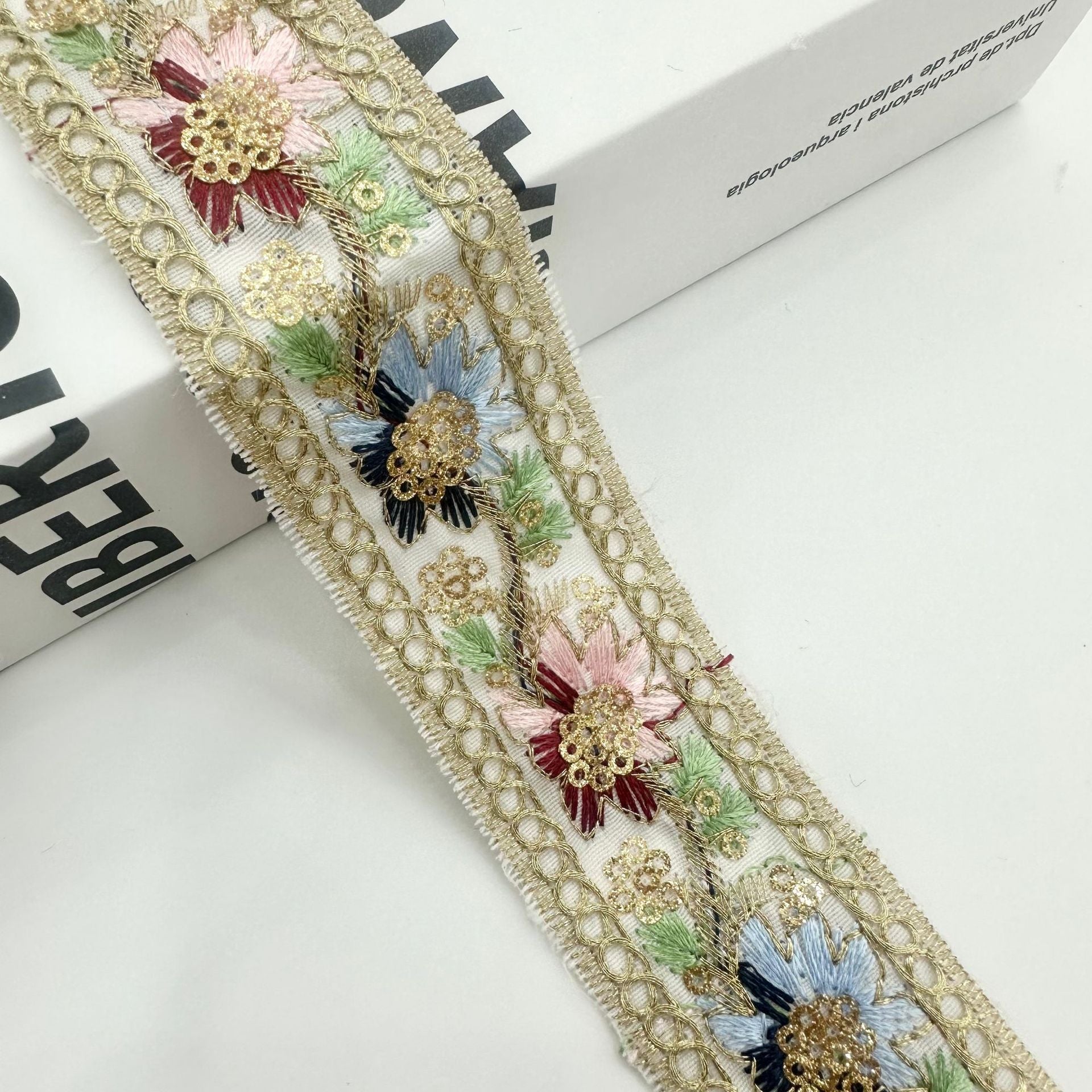 Gold-tone ribbon trim with blue and pink floral sequin embroidery on mesh ground