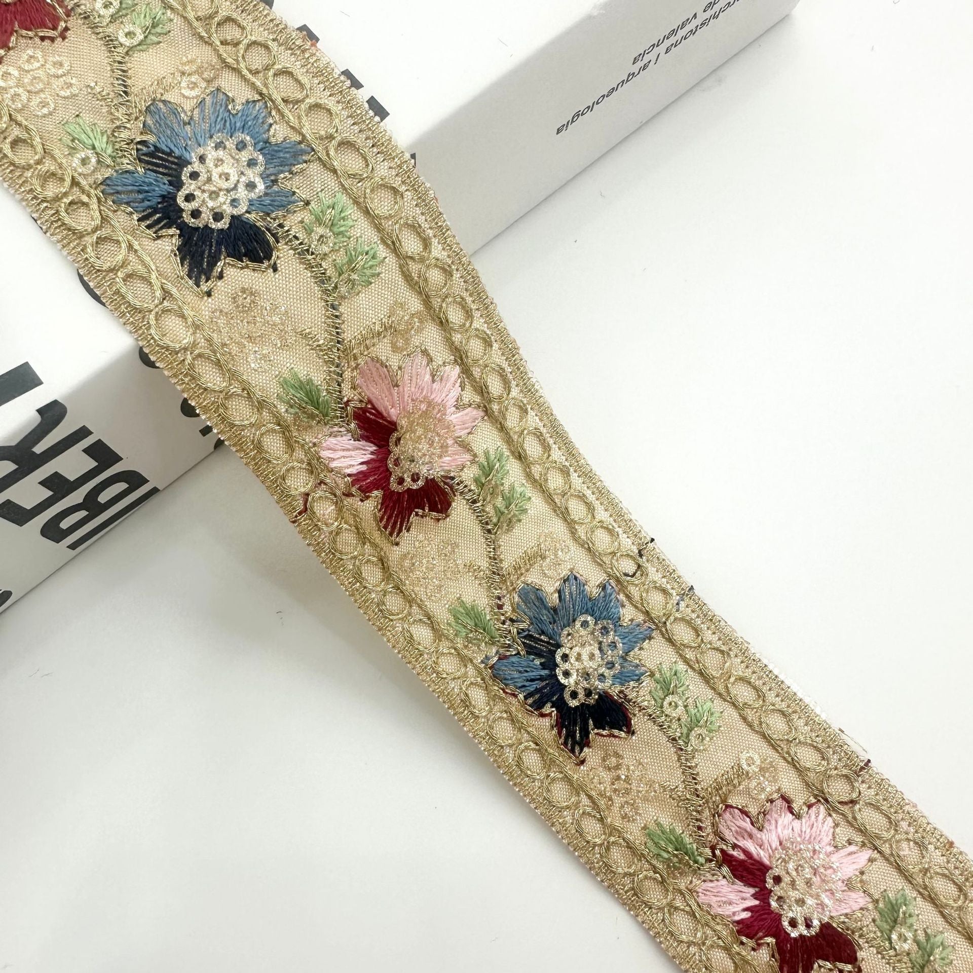 Gold-tone ribbon trim with blue, pink, and red flower sequins and ornate border
