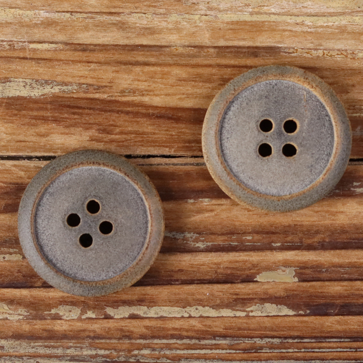 Pair of matte buffalo horn buttons with burnt edges and four holes each
