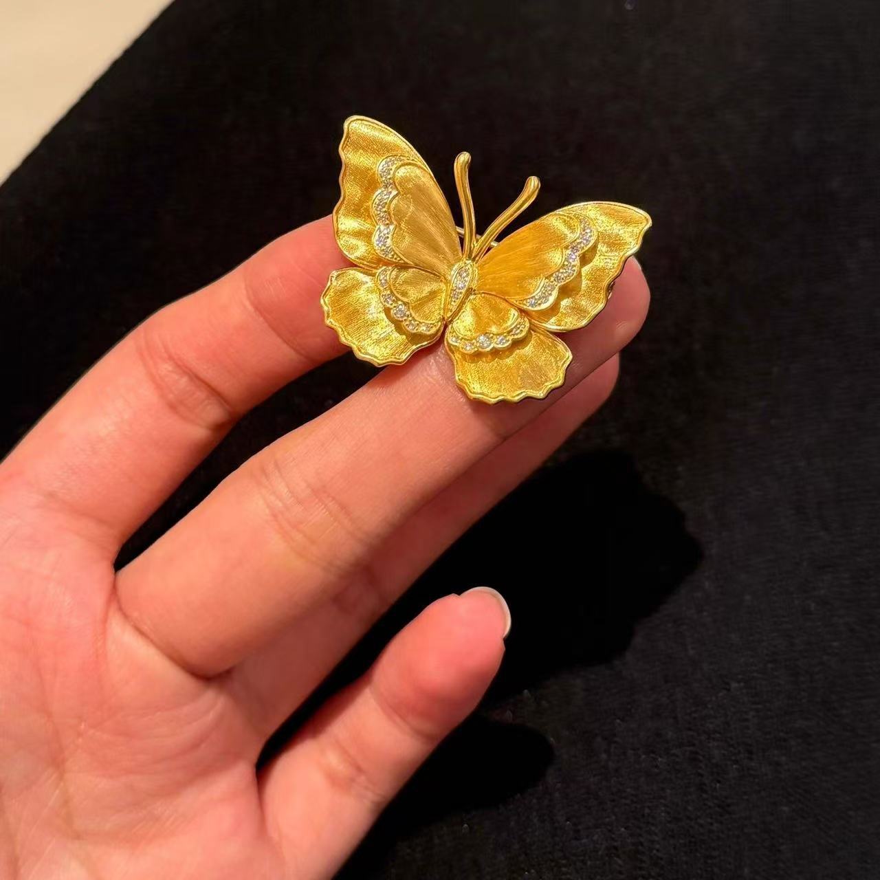 Gold brushed butterfly brooch pin with matte vintage finish and rhinestone detail