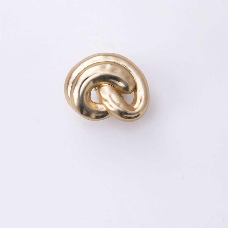 Gold ear-shaped metal shank button, close-up swirl front