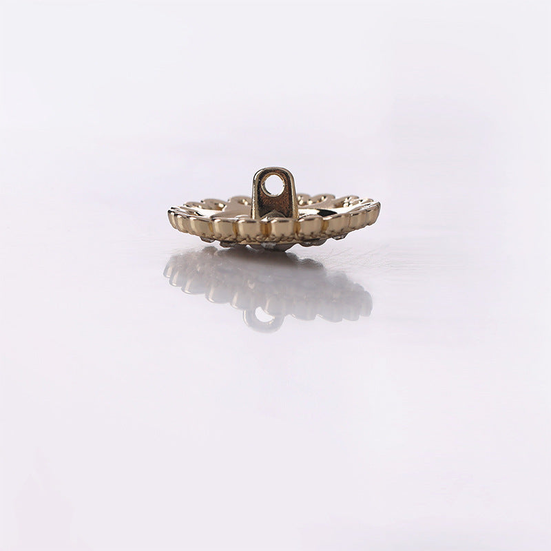 Side view of gold metal shank button with raised lace filigree rim