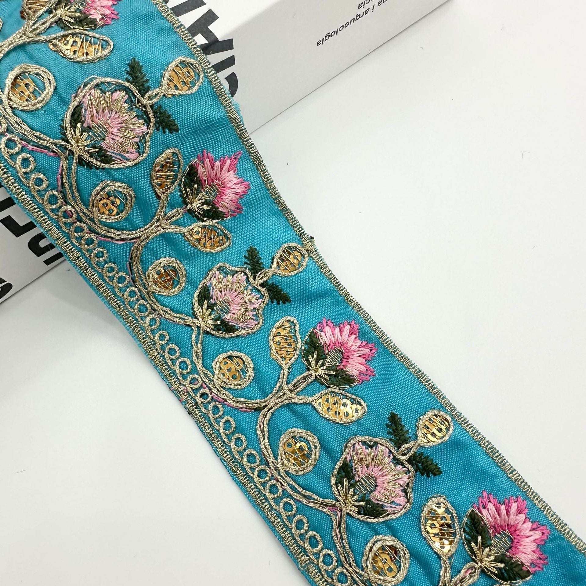Teal embroidered lace trim ribbon with pink blooms, gold bead circles, and scalloped trim