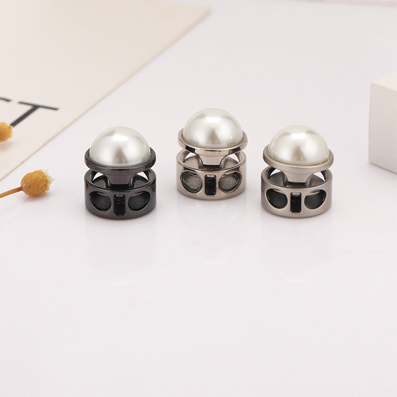 Three metal two-hole cord locks with pearl dome tops in gunmetal and silver