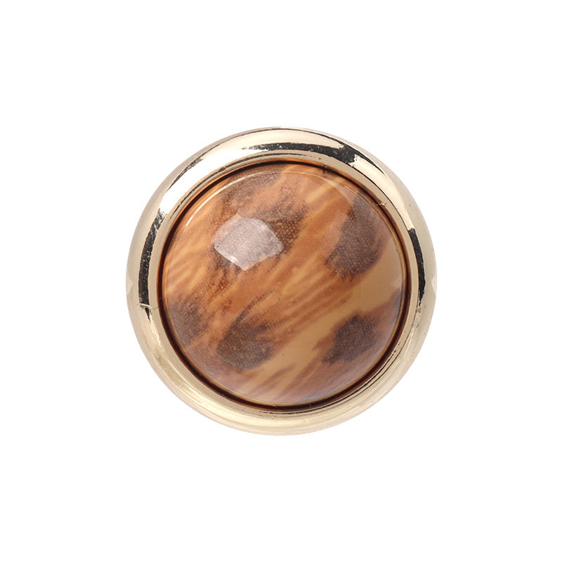 Mushroom resin button with leopard-print brown pattern, gold rim, round front close-up