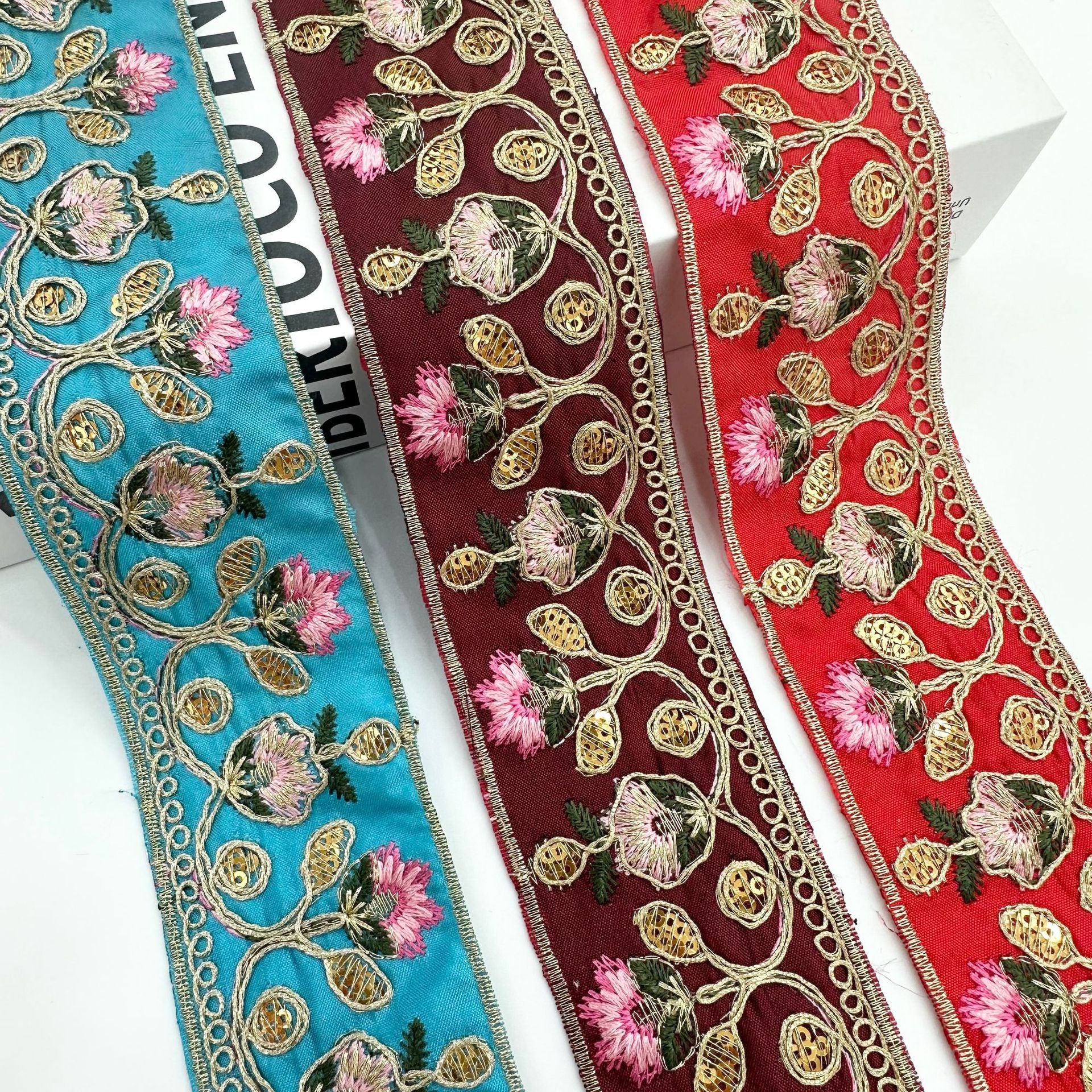 Embroidered lace trim ribbon in teal, burgundy, and red with pink flowers and gold details