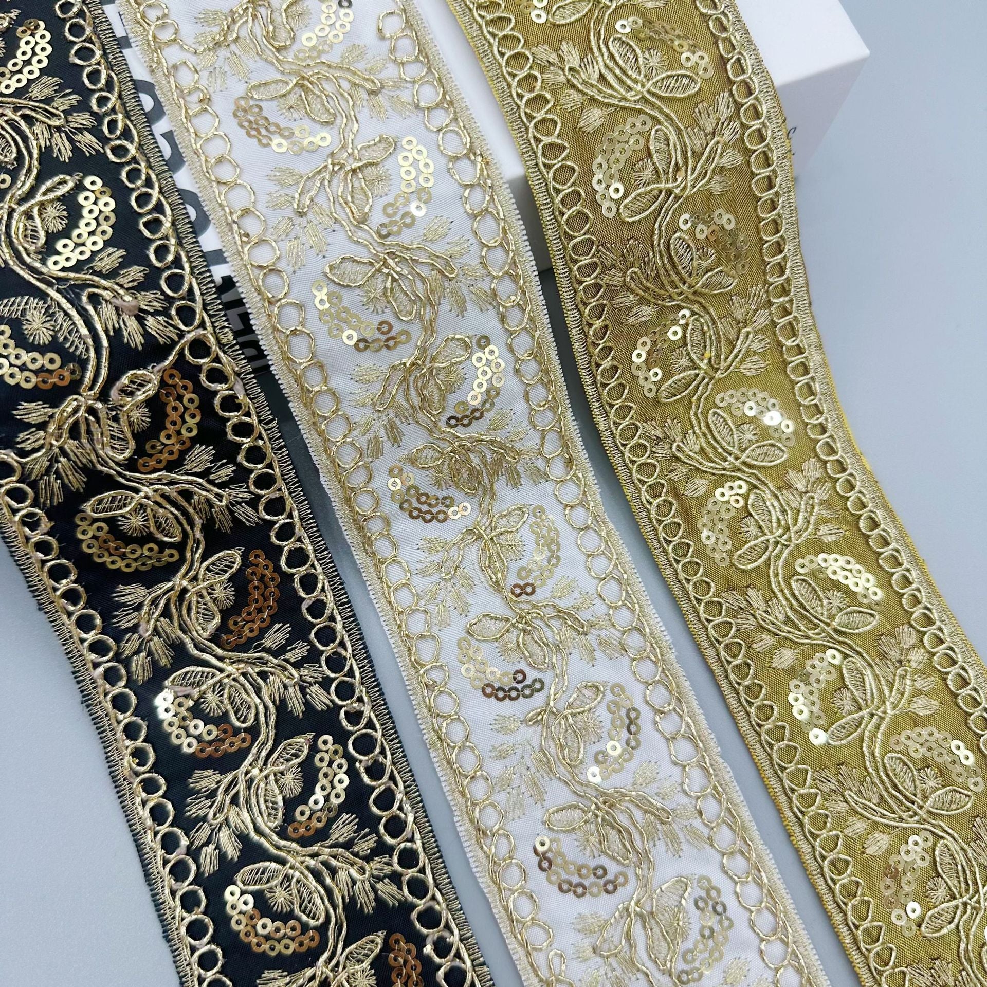 Gold sequin embroidered lace trim ribbon set on dark, white, and olive fabrics