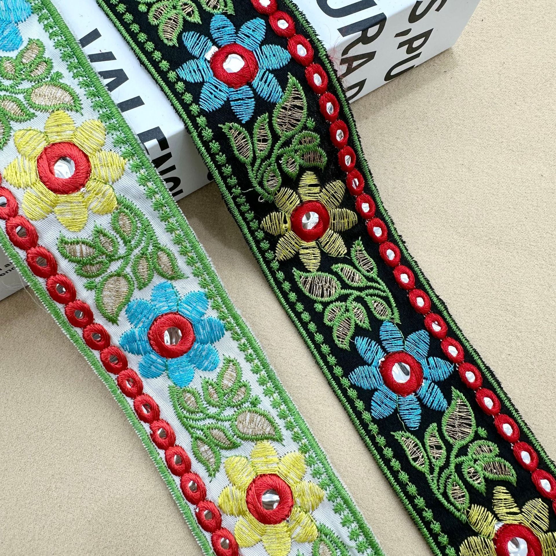 Sunflower lens lace trim with red ring motifs, green border, blue and yellow flowers on dark base