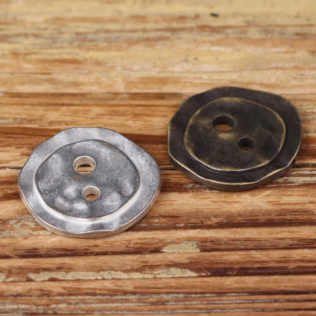 Irregular metal 2-hole buttons, silver and bronze finishes, round face with two holes.