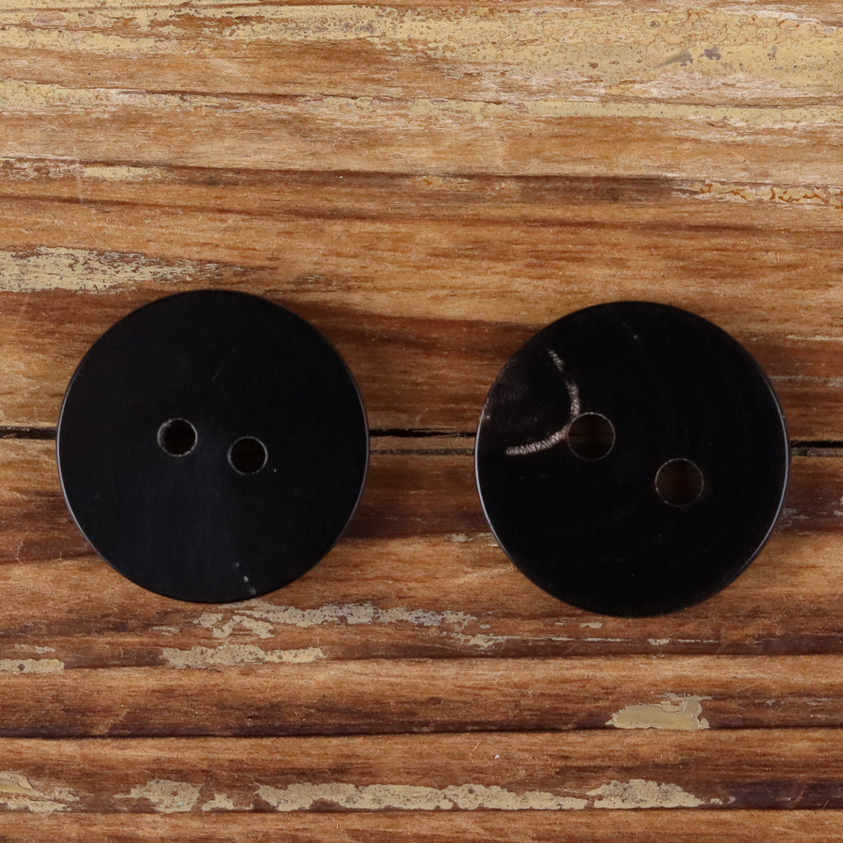 Two-hole round black horn button, matte burnt-edge finish