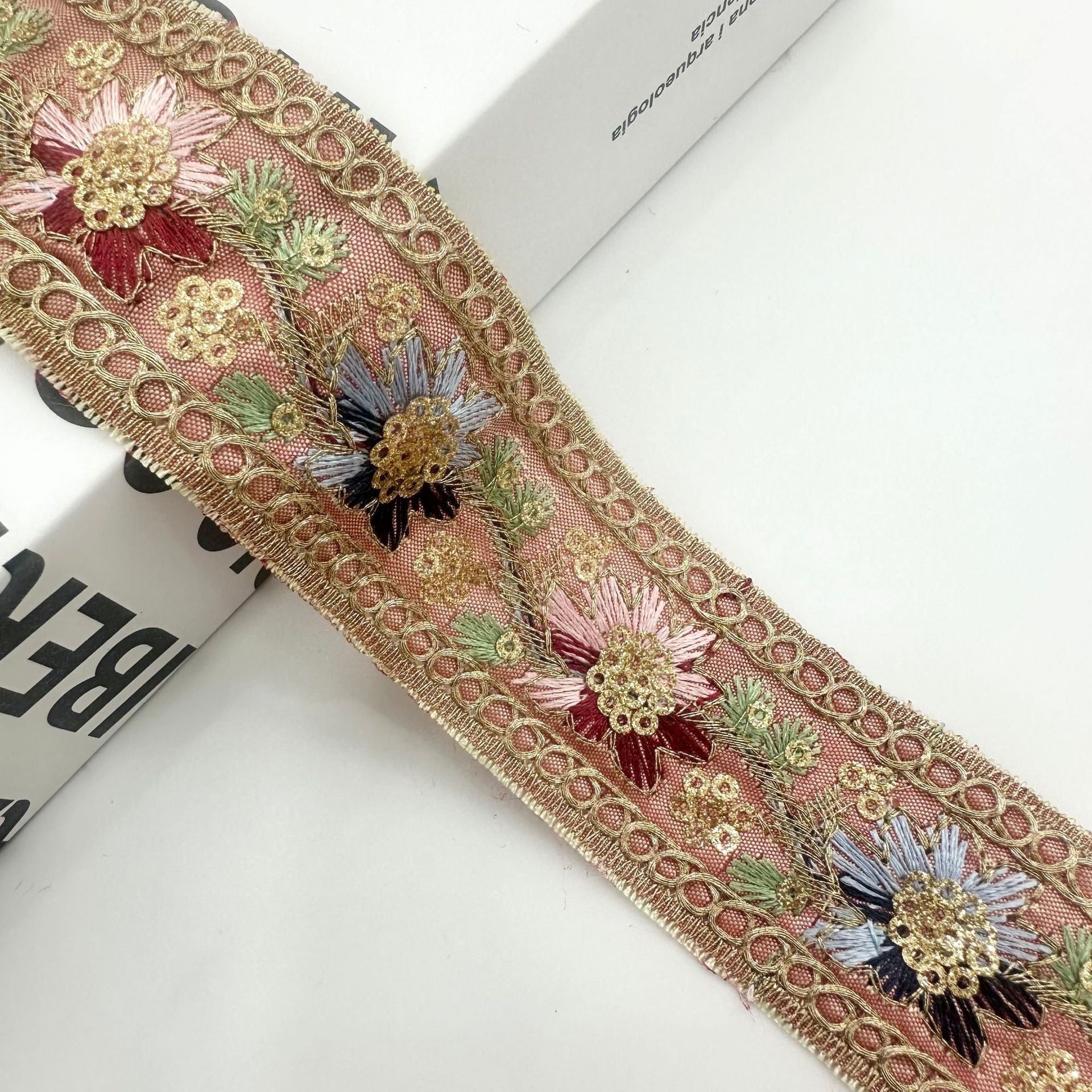 Rose-gold embroidered ribbon trim with pink and blue sequined flowers and green accents
