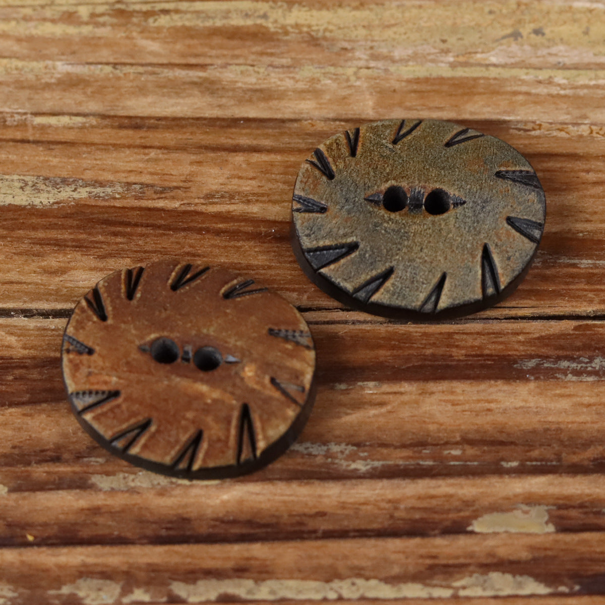 Oval two-hole horn buttons in brown and grey, carved radial pattern and two holes.