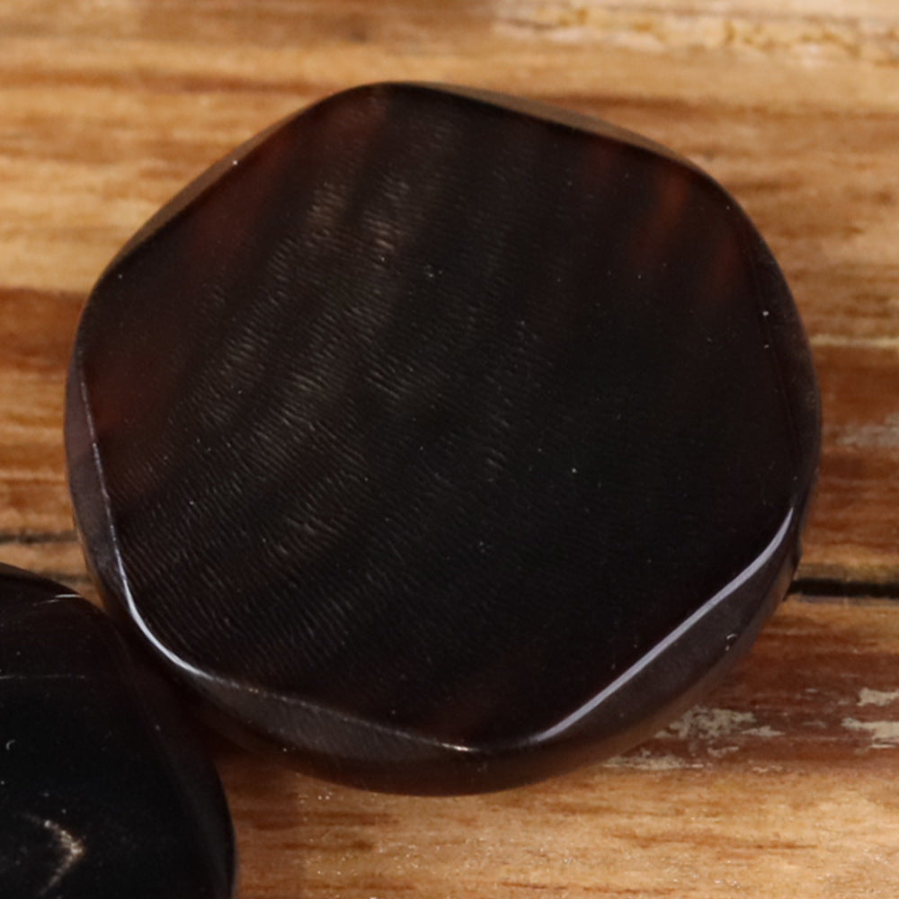 Buffalo horn button in dark brown with irregular edge and hidden eye detail